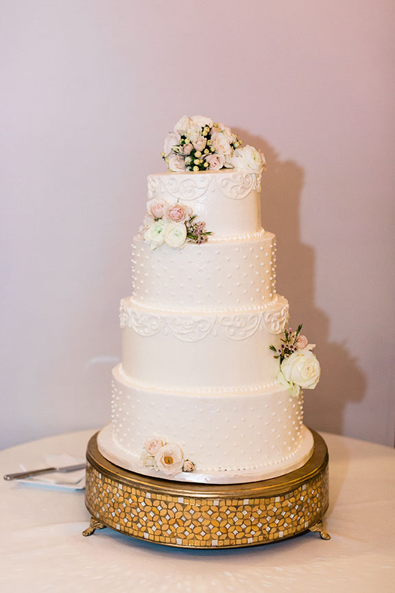 White Swiss Dotted Four-Tiered Wedding Cake on Gold Stand