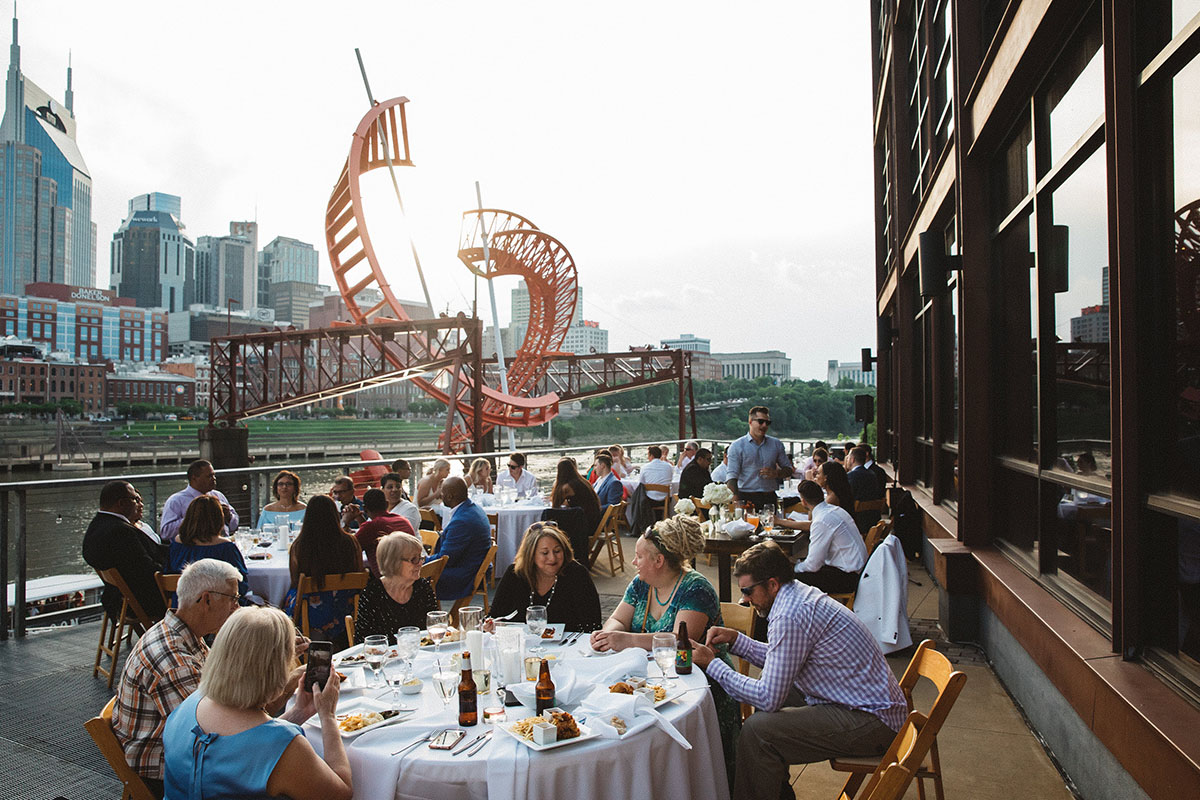 Guests Enjoying Dinner on Bridge Building's Riverfront Patio