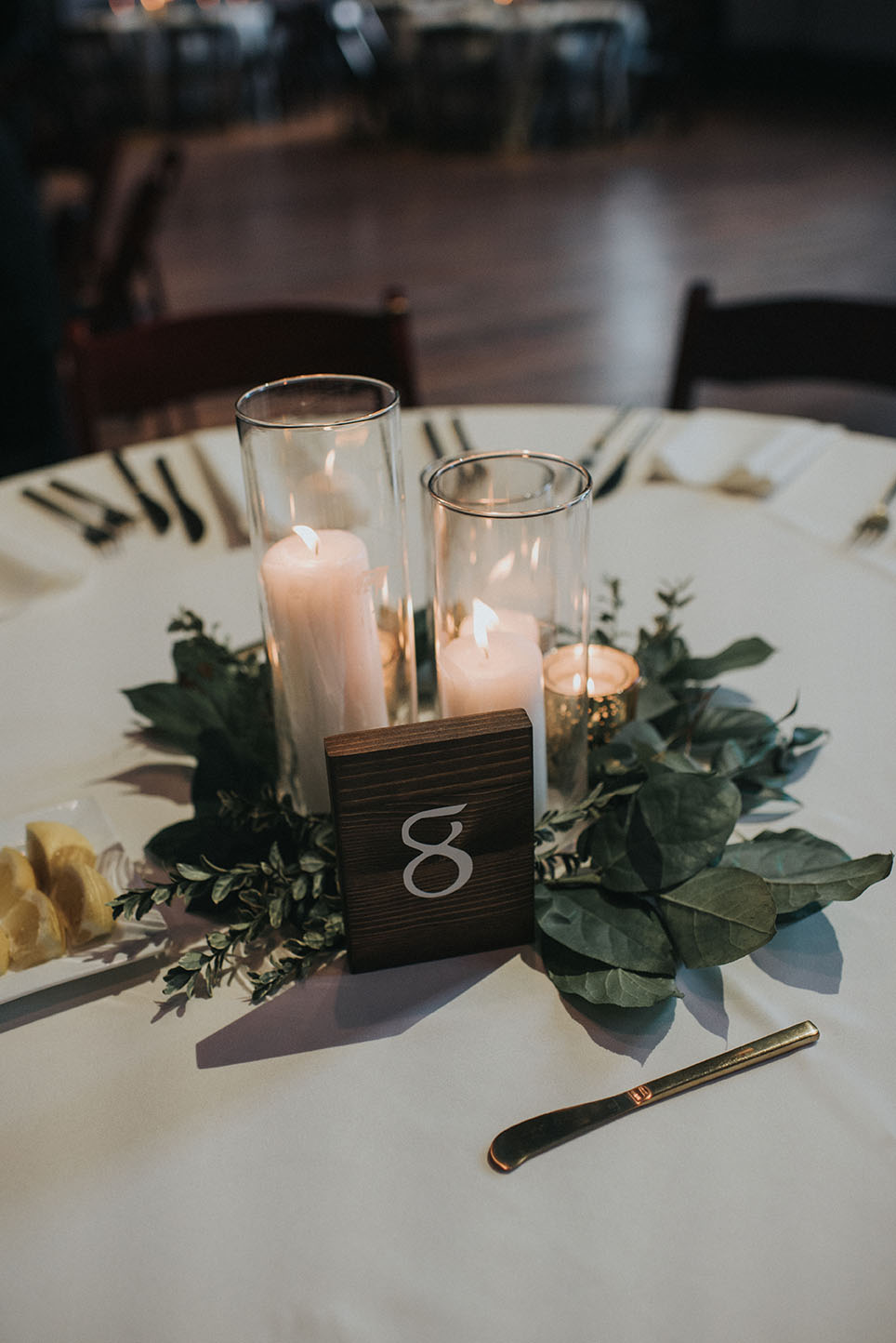 Simple Organic White Pillar Candle Greenery Centerpiece With Wooden Table Number