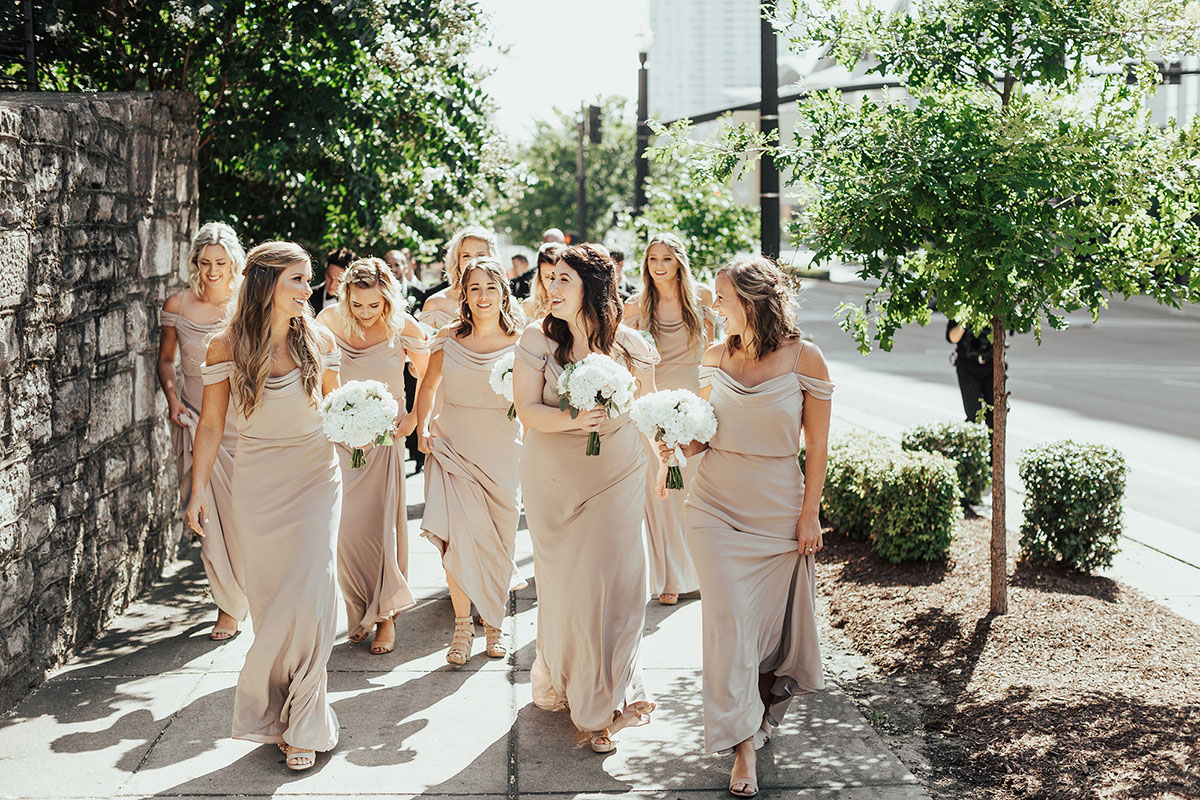 Bridesmaids Walking Outside of the Bell Tower Wearing Neutral Dresses