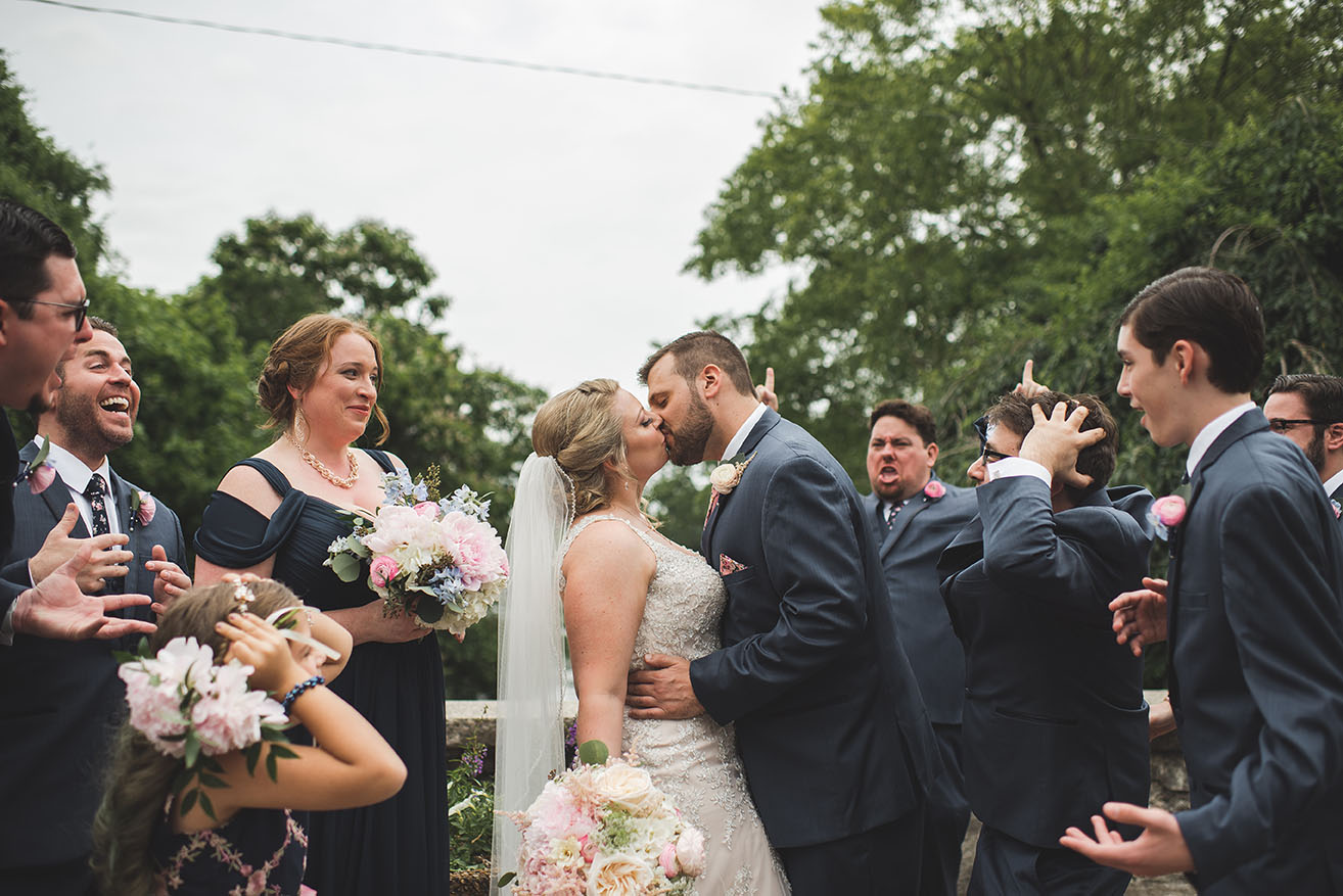 Nicole and Chris Kissing While Wedding Party Cheers