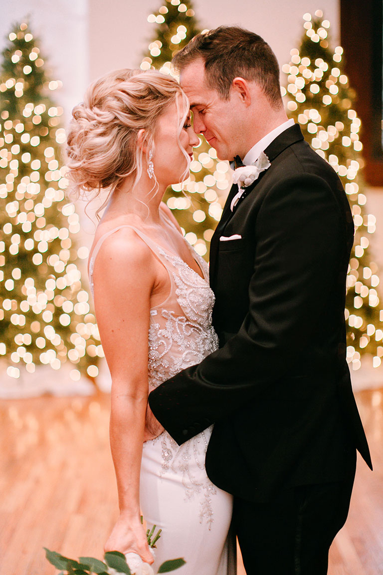 Bride and groom touching foreheads in front of Christmas wedding ceremony altar