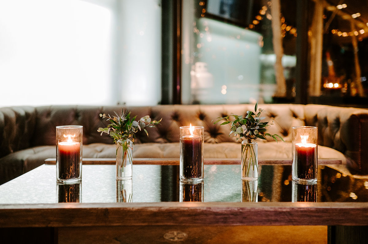 Pillar Candles and Bud Vases with Sprigs of Greenery Sitting on Coffee Table