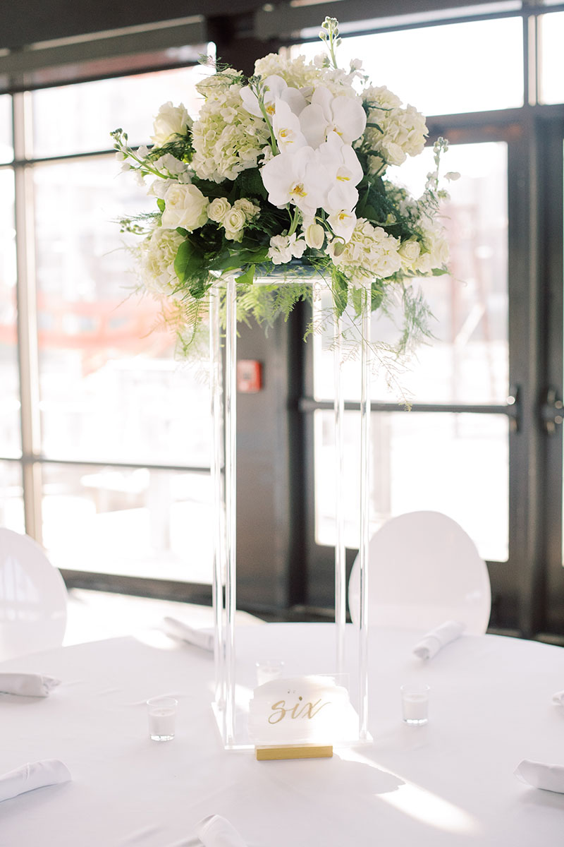 All white wedding reception table with tall modern floral centerpiece