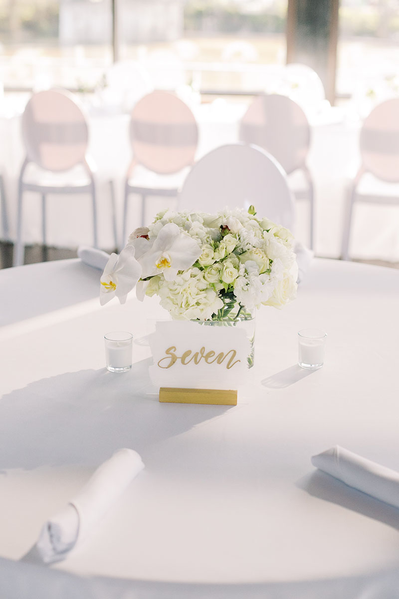 All white wedding reception table with small hydrangea centerpiece and white acrylic table number