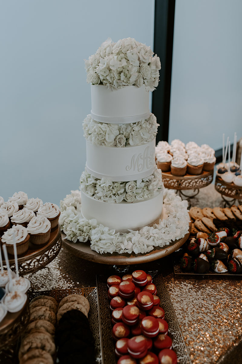 Gold sequined linen dessert table with three tier white wedding cake