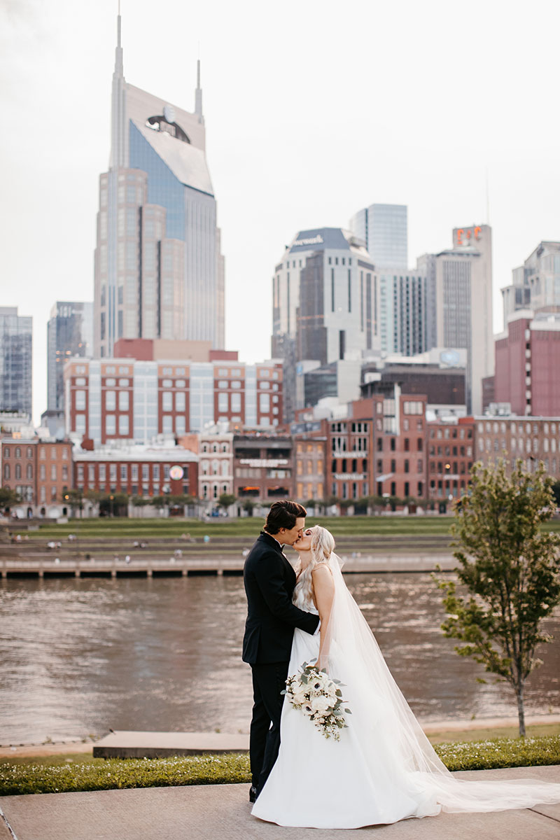 Bride and Groom Kissing on the Riverfront in Front of the Nashville Skyline