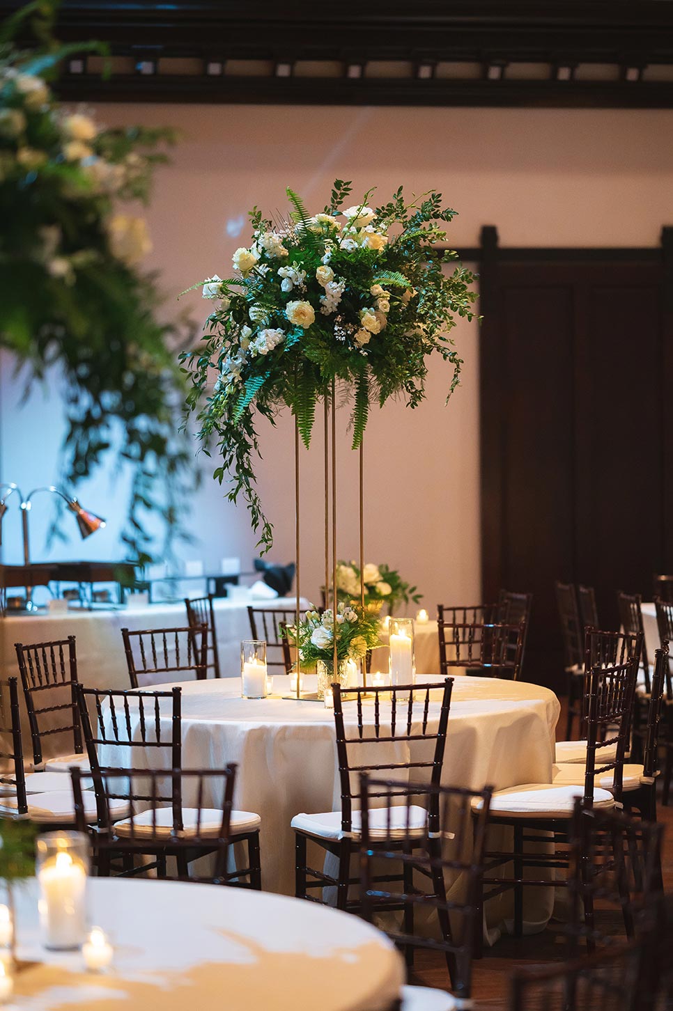 Reception with white linens elevated floral centerpieces and romantic pillar candles