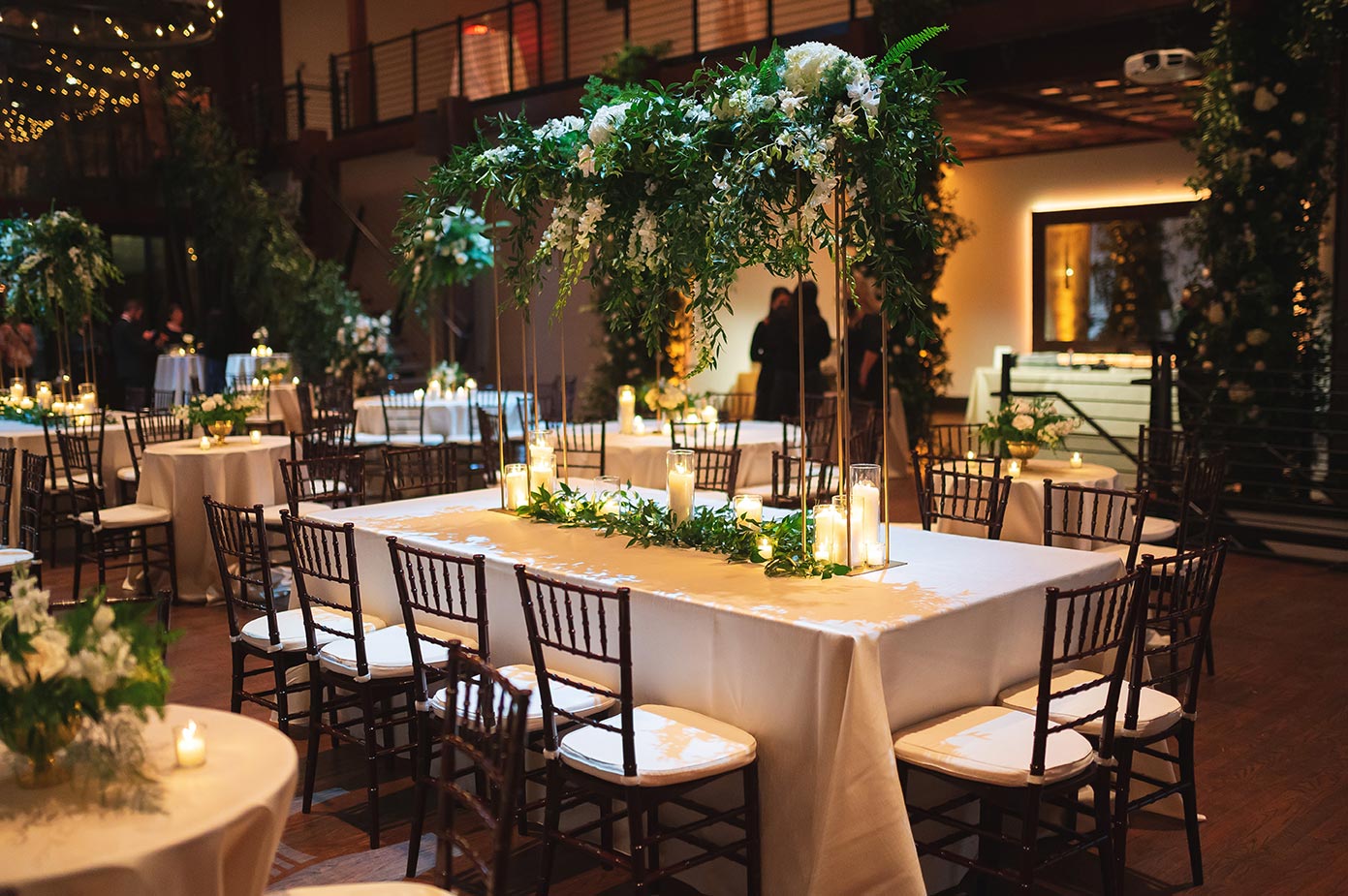 Kings table with white linen elevated greenery and white roses