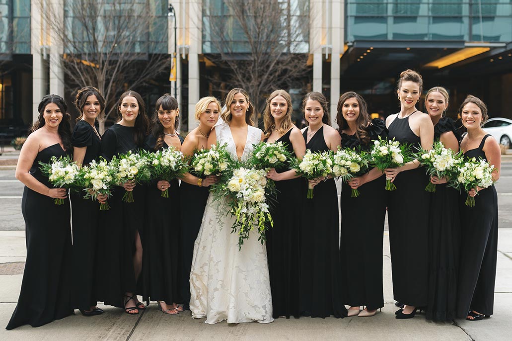 Bridal part poses with black dresses and coordinating floral bouquets