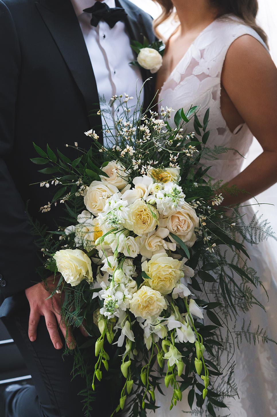Bride holds a stunning, cascading bouquet full of wild greenery and bright white blooms.