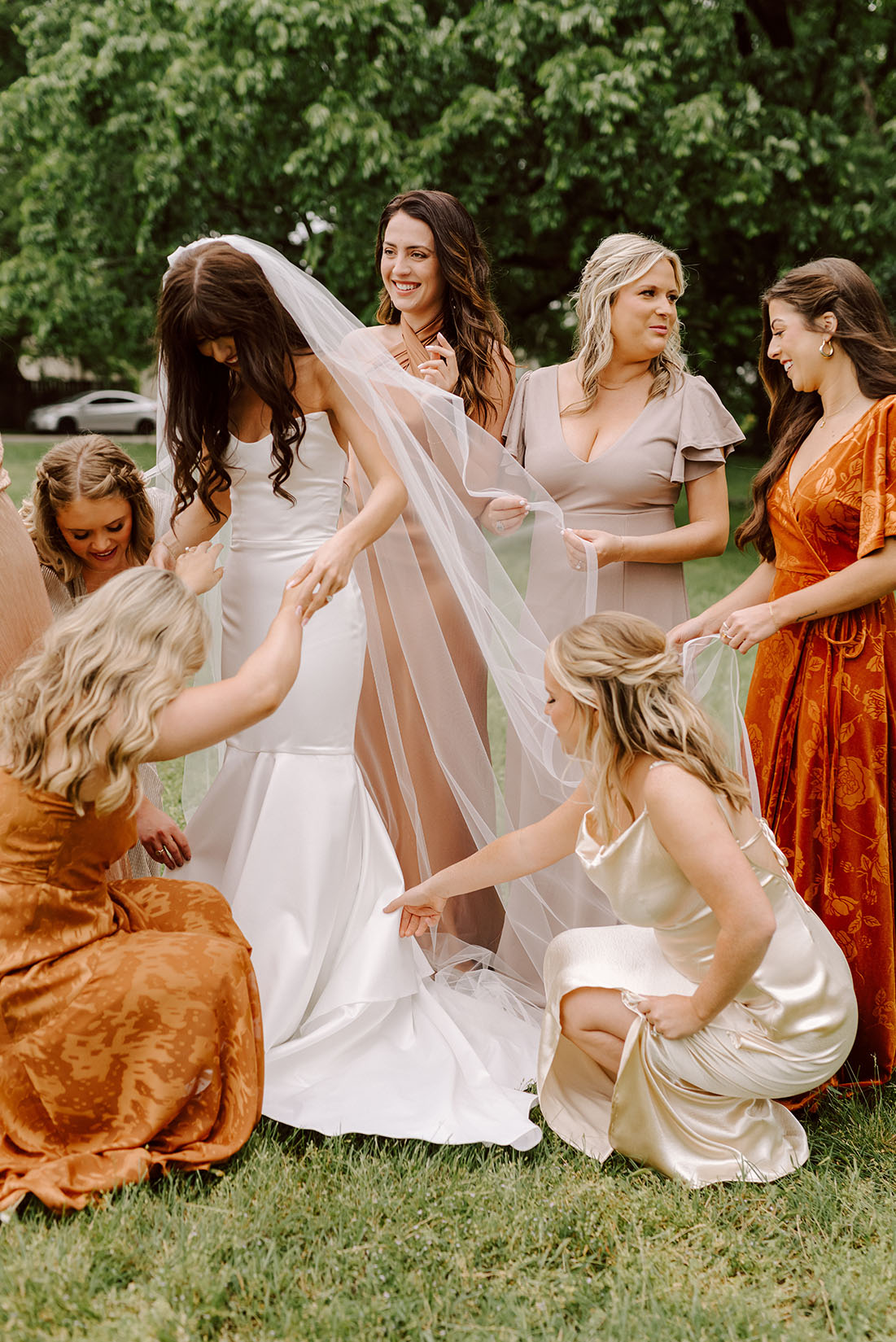 Bridesmaids wearing mix-and-match rust and neutral dresses