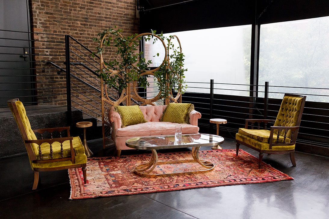 Bohemian wedding reception lounge area with rattan room divider, vintage velvet furniture and oriental rug