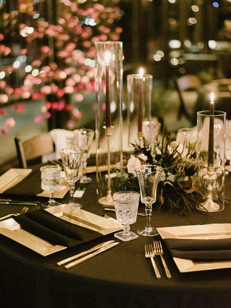 Moody black and gold wedding reception table setting with taper candles