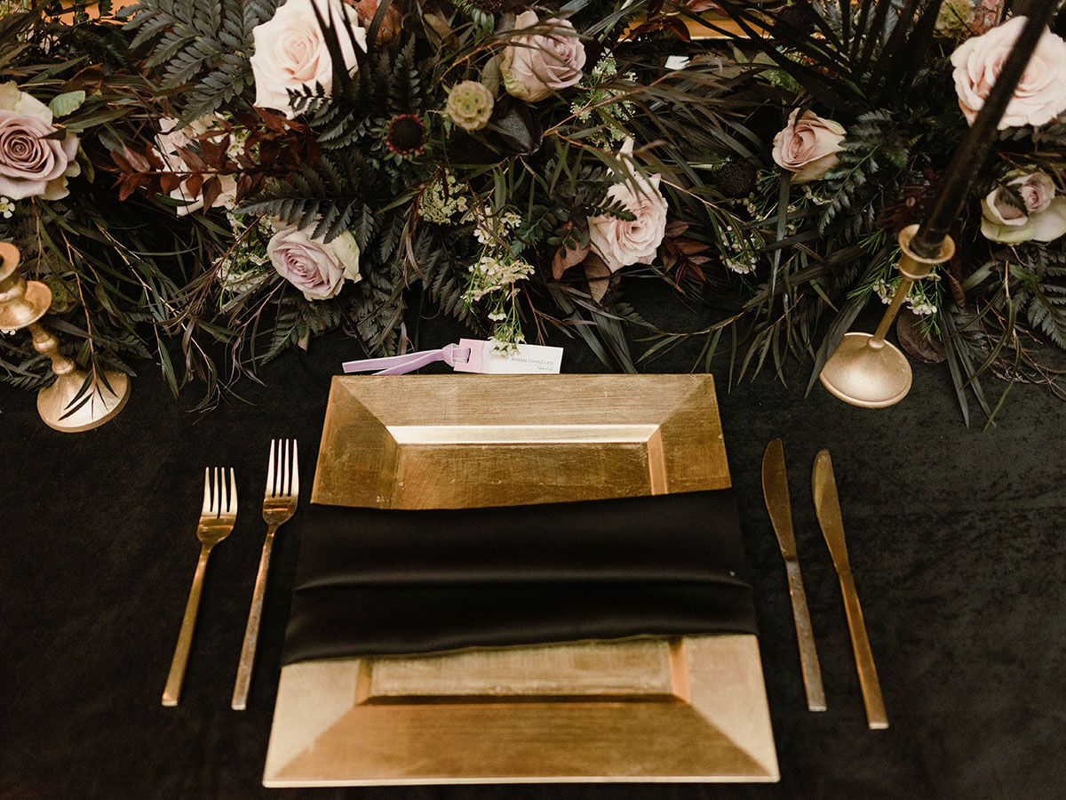 Table Setting for Reception with gold chargers and moody floral centerpiece
