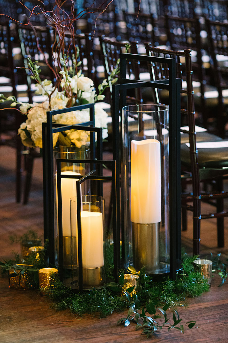 Tall Pillar Candles in Hurricane Vases with Modern Black Frames Decorated with White Florals and Greenery | Wedding Ceremony Aisle Decor Inspiration