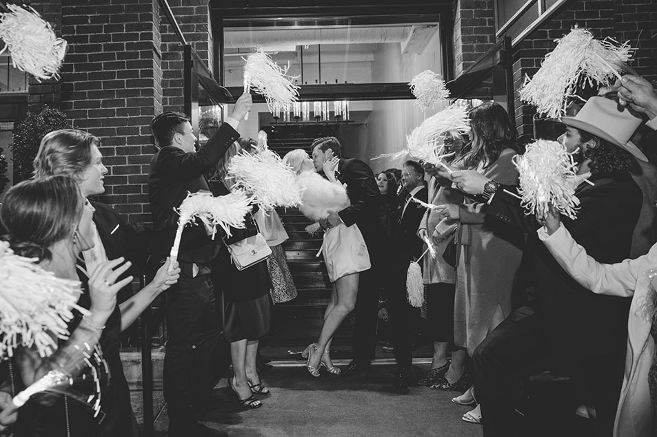 Bride and groom leave the wedding reception as guest wave pom poms