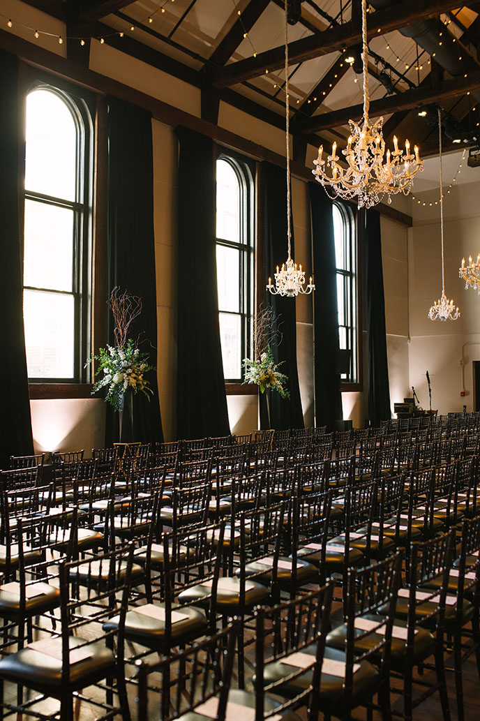 Classic Black Tie Wedding Ceremony with Hanging Glamorous Chandeliers, String Lighting, and Moody Black Drapes