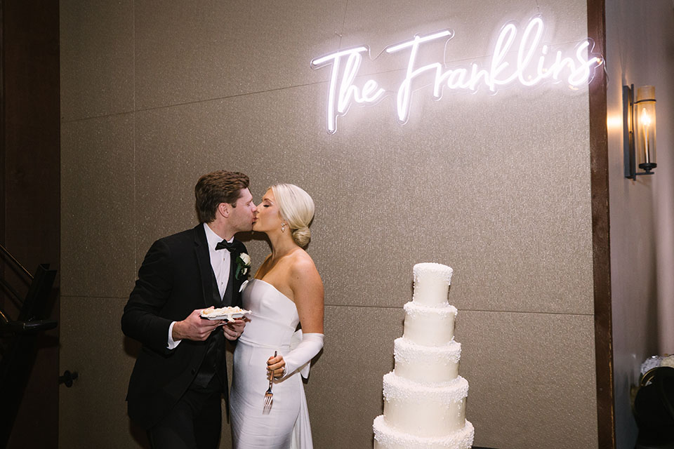 Classic Bride and Groom Pose Under Custom LED Neon Wedding Sign for Cake Cutting | Traditional White 5-Tier Wedding Cake