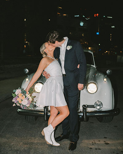 Emily and Tyler Kissing After Wedding in Downtown Nashville infant of Exit Car