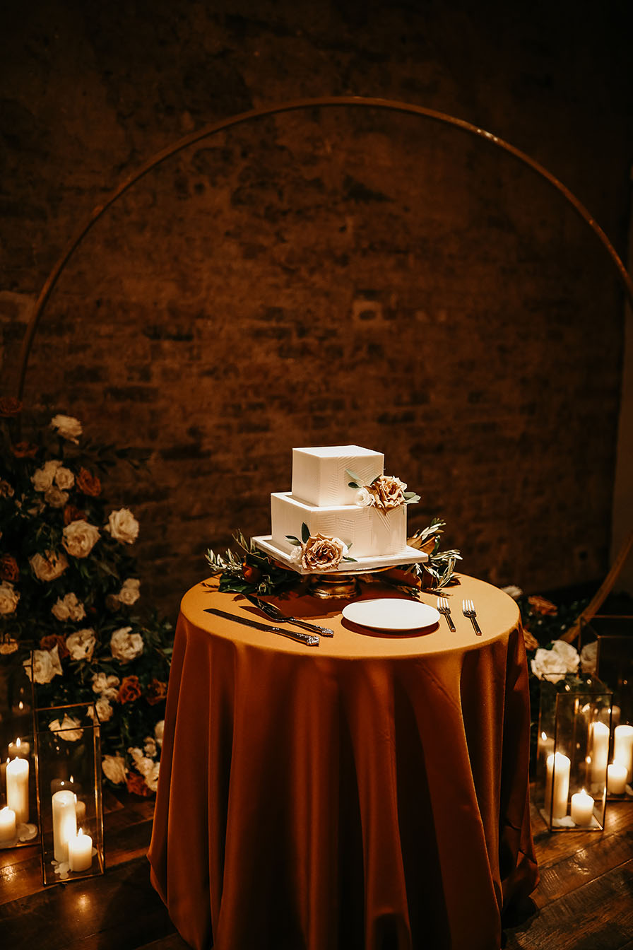 Square Tiered Wedding Cake Sitting on Rust-Colored Linen