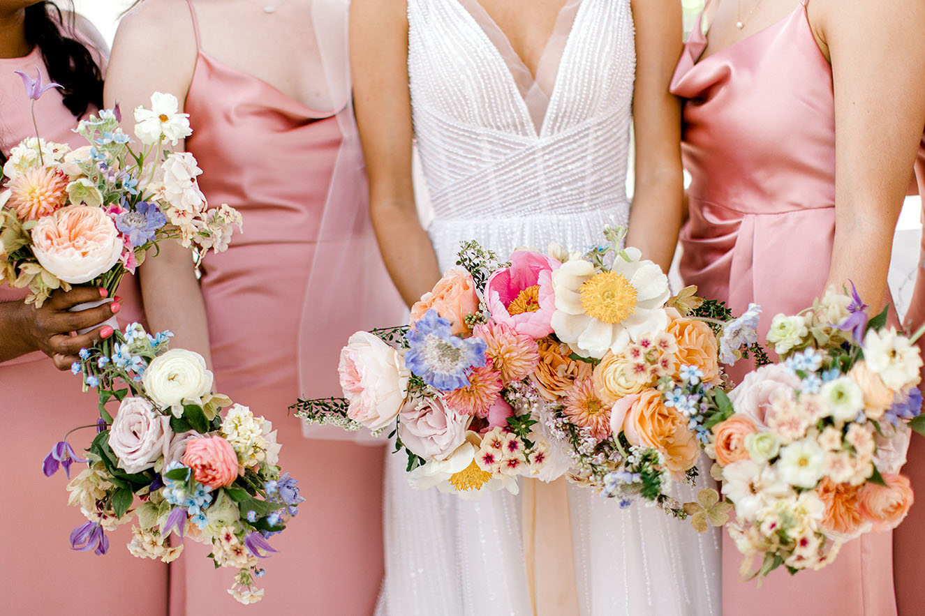 Bridesmaids holding colorful spring wedding bouquets wearing pink dresses