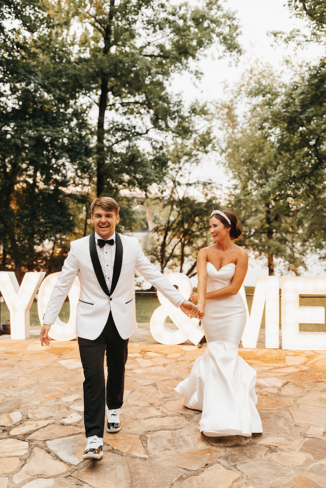 Bride and groom walking on patio in front of marquee letters