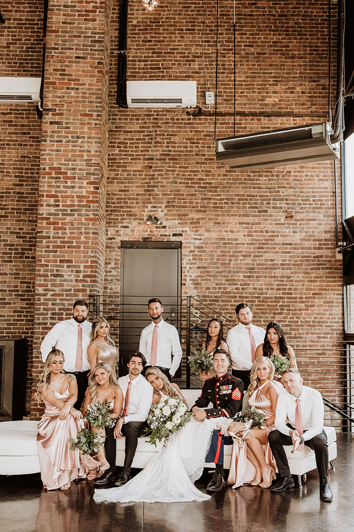wedding party poses on the bell towers patio bridesmaids wearing sating light pink dresses and groomsmen wearing coordinating ties