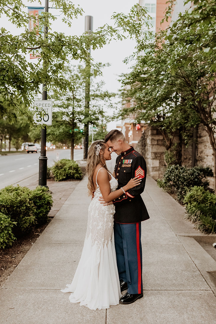 groom in military uniform holds his bride outside the bell tower in downtown nashville