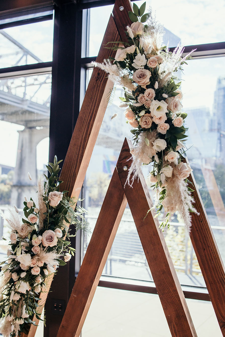 Modern boho triangular wedding ceremony arch with pampas grass and florals
