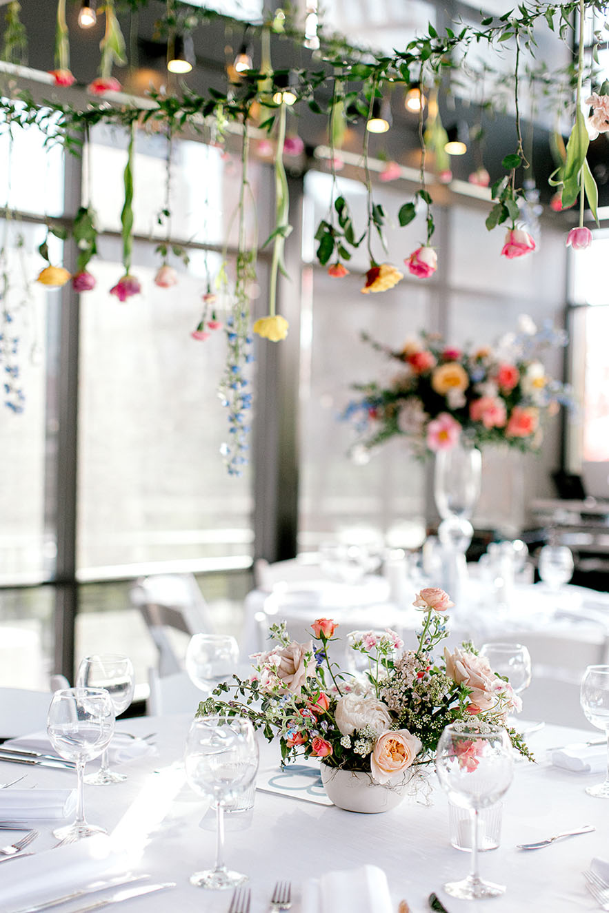 Spring wedding reception table with colorful hanging floral installation at Nashville wedding venue The Bridge Building