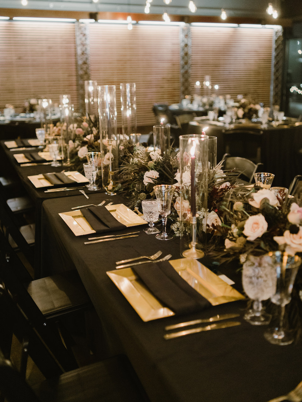 Moody October wedding reception table setting with black taper candles and gold chargers