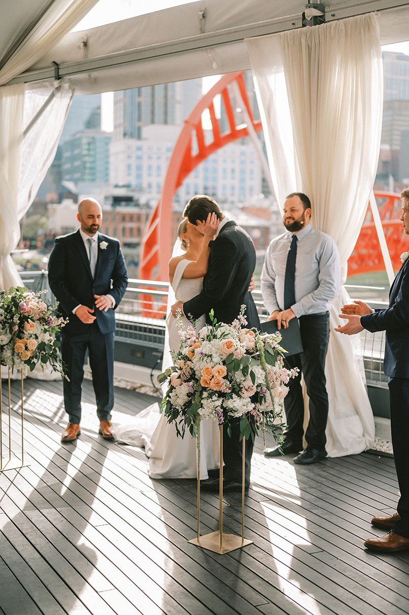 Emily and Tyler's First Ceremony Kiss for Whimsical Wedding on Rooftop in Nashville