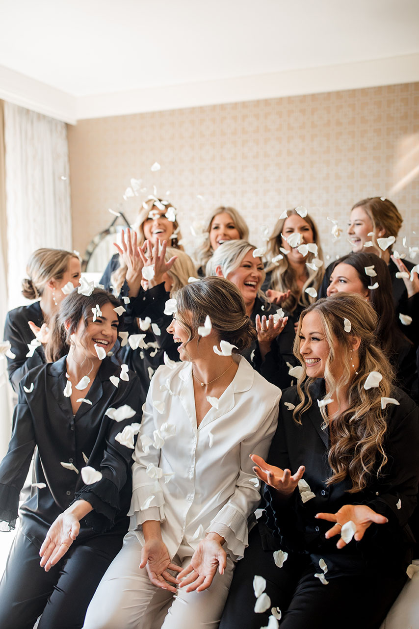 bridesmaids throw floral petals in the hotel room while getting ready