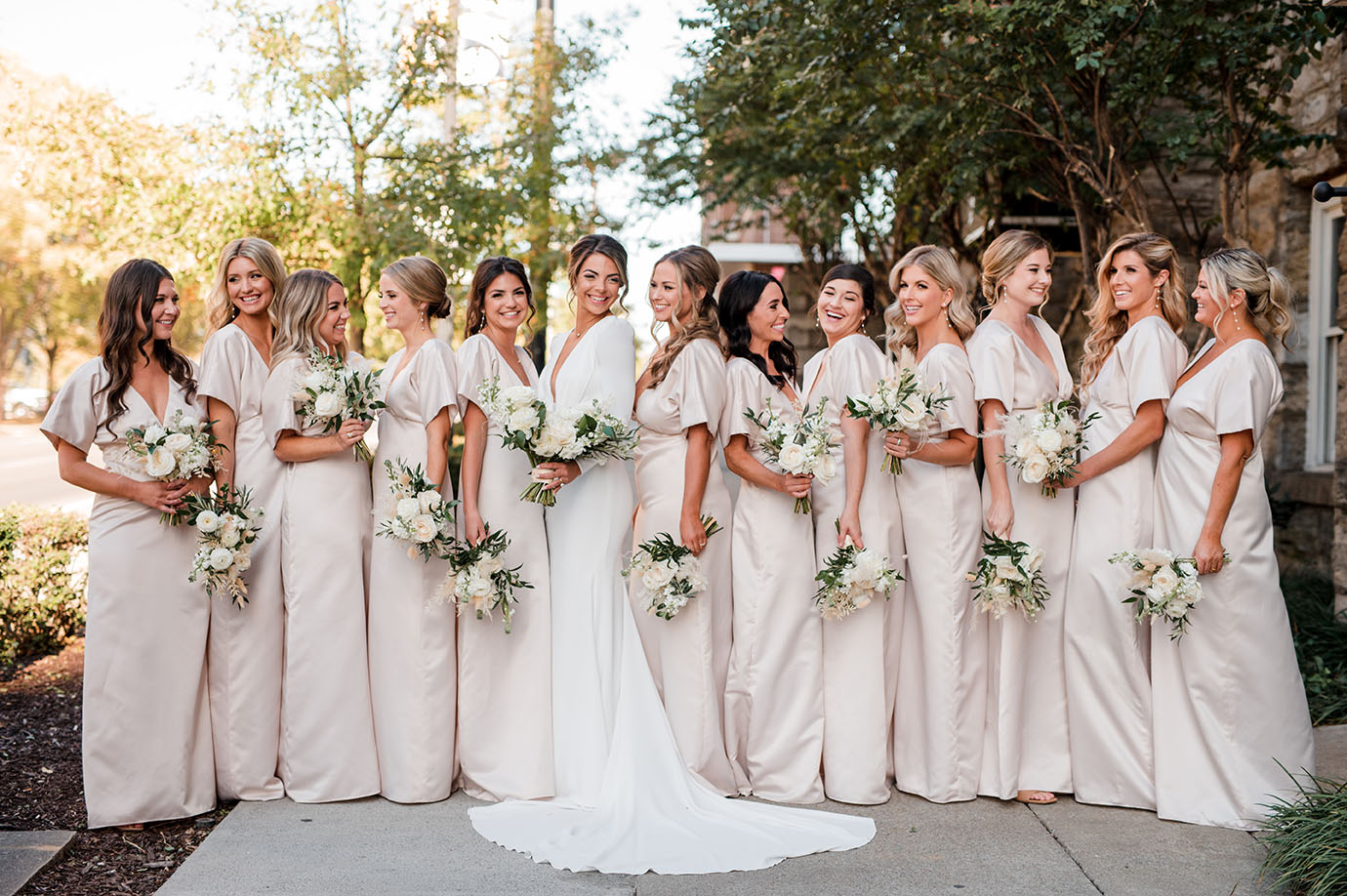 Kristen and bridesmaids wearing custom matching soft pink gowns while carrying posy versions of her bridal bouquet