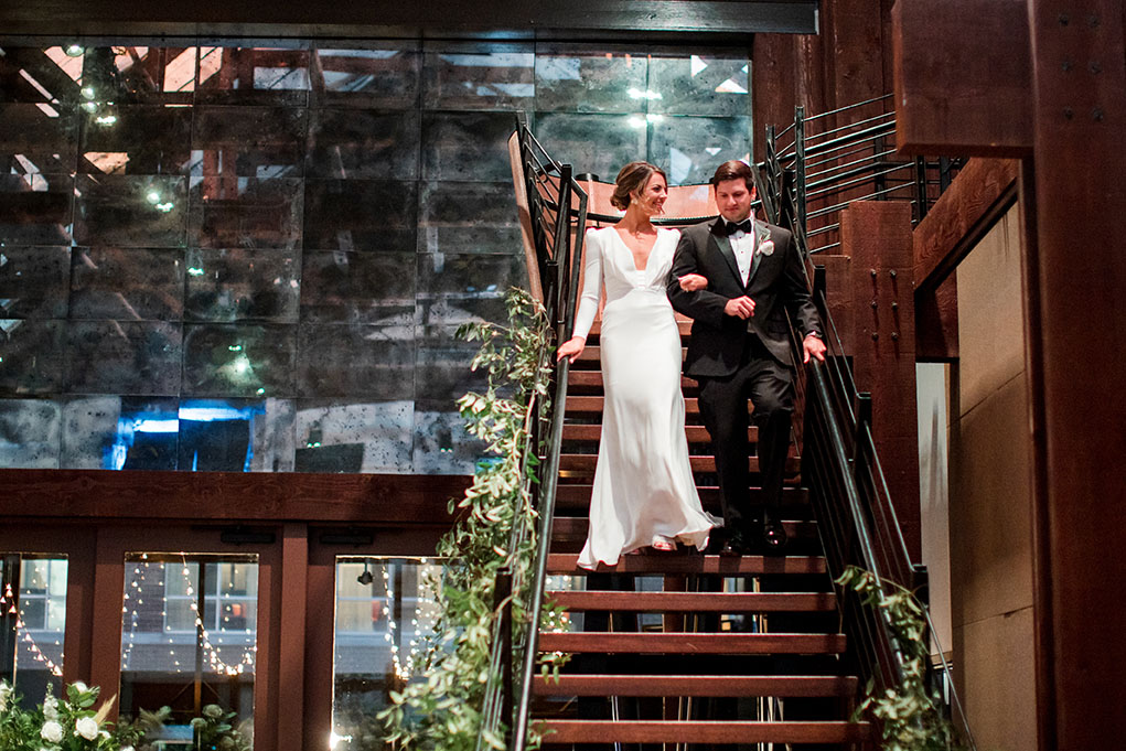 bride and groom entering the reception down the staircase