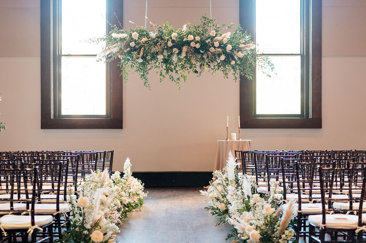 ceremony set up with hanging floral installation and boho florals lining the aisle