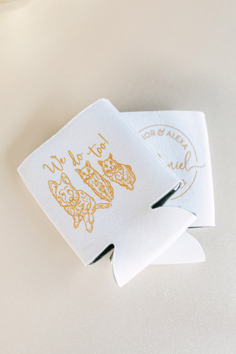 Custom wedding day koozies that read "We do, too!" with illustration of couple's pets