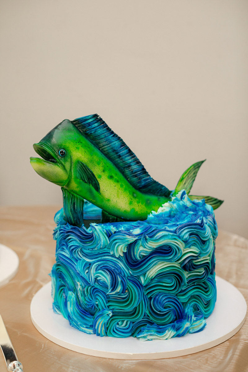 Groom's cake decorated with green mahi mahi fish on top and blue buttercream that looks like waves