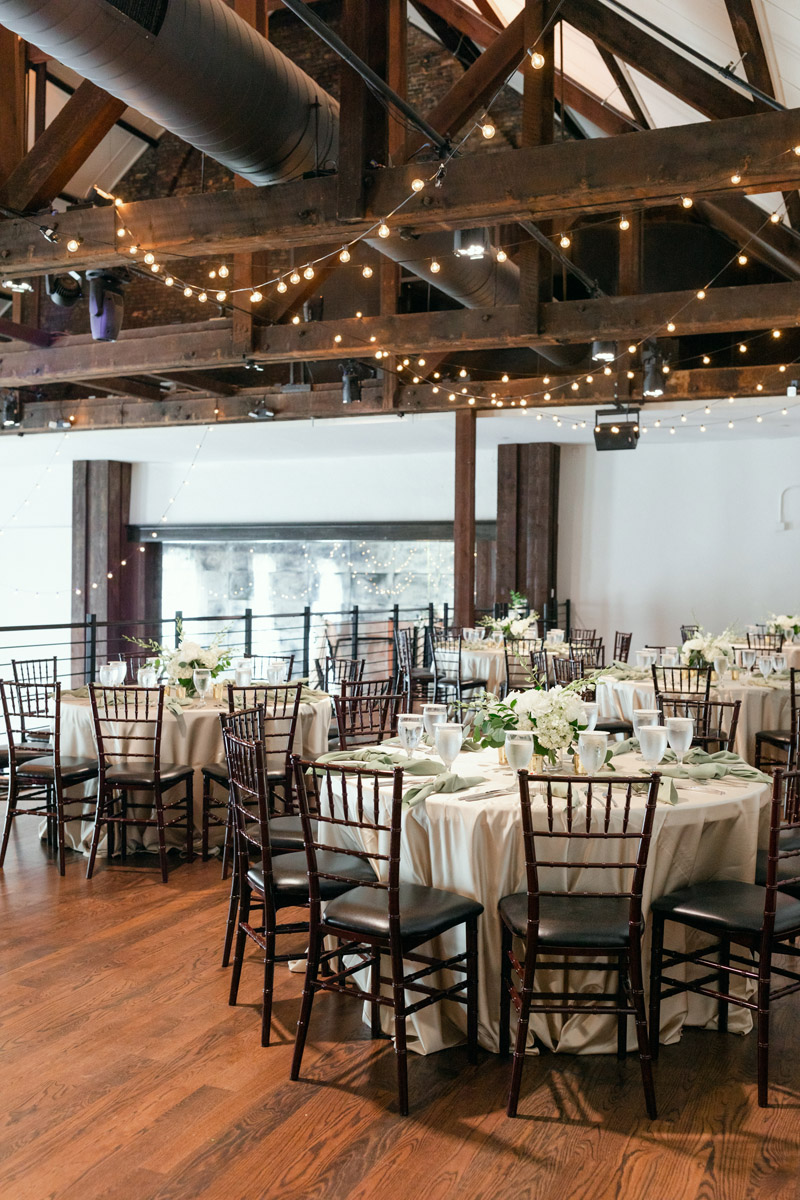 Round wedding reception tables with ivory linens and classic round white floral centerpieces