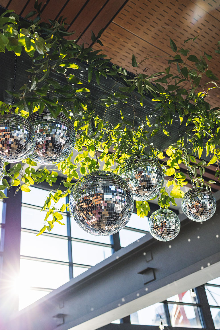 Greenery Install with disco balls hanging from industrial beams