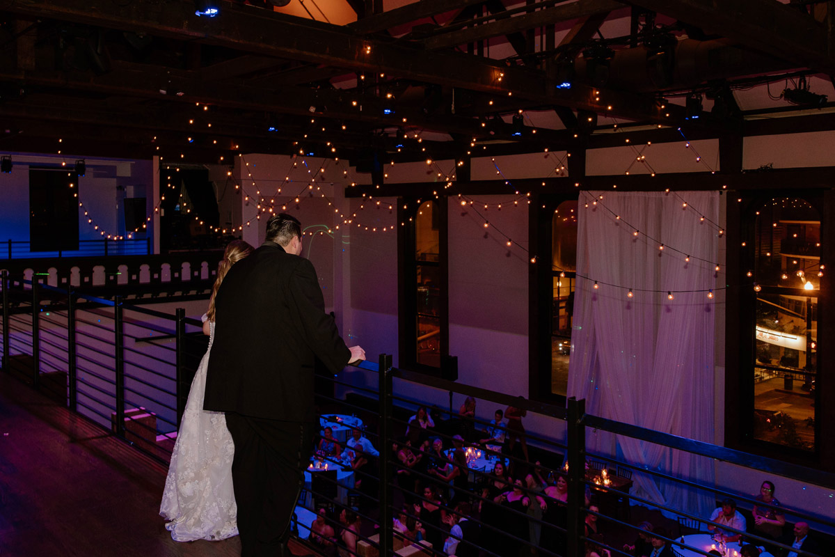 Bride and groom look over their reception from the mezzanine of The Bell Tower