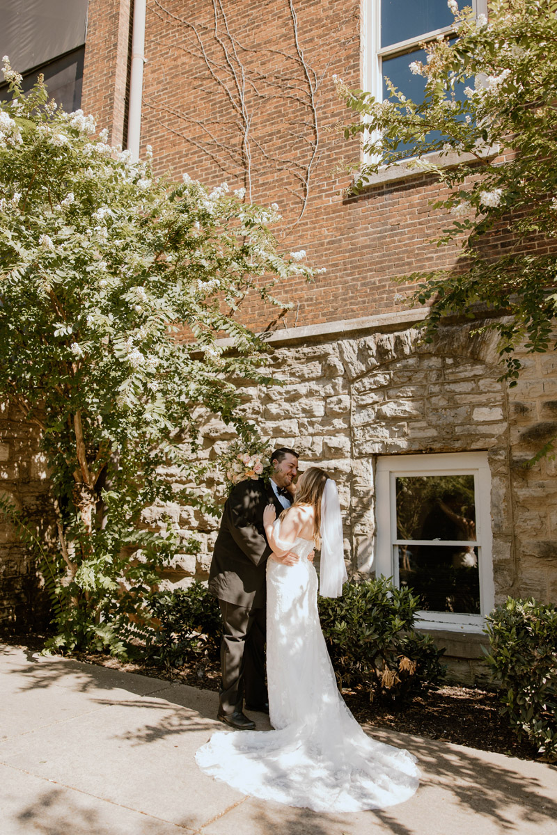 bride poses with groom outside historical old church turned wedding venue in downtown nashville