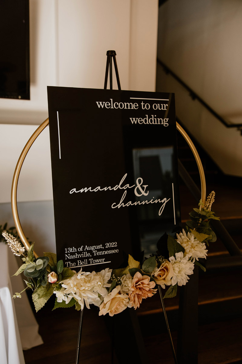 black wedding signage with gold floral circle set on an easel