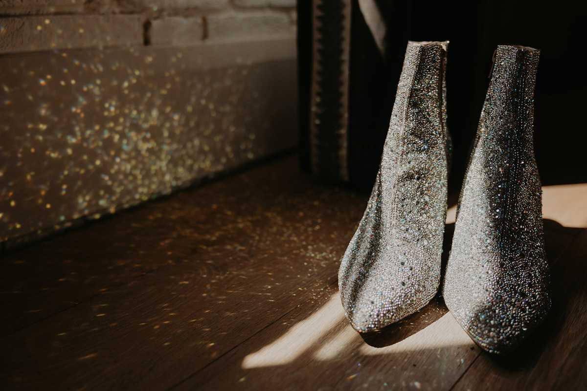 A close-up of sparkling silver ankle boots shimmering in window light
