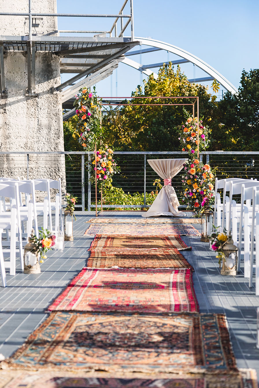 Vibrant boho wedding ceremony aisle decorated with oriental rugs