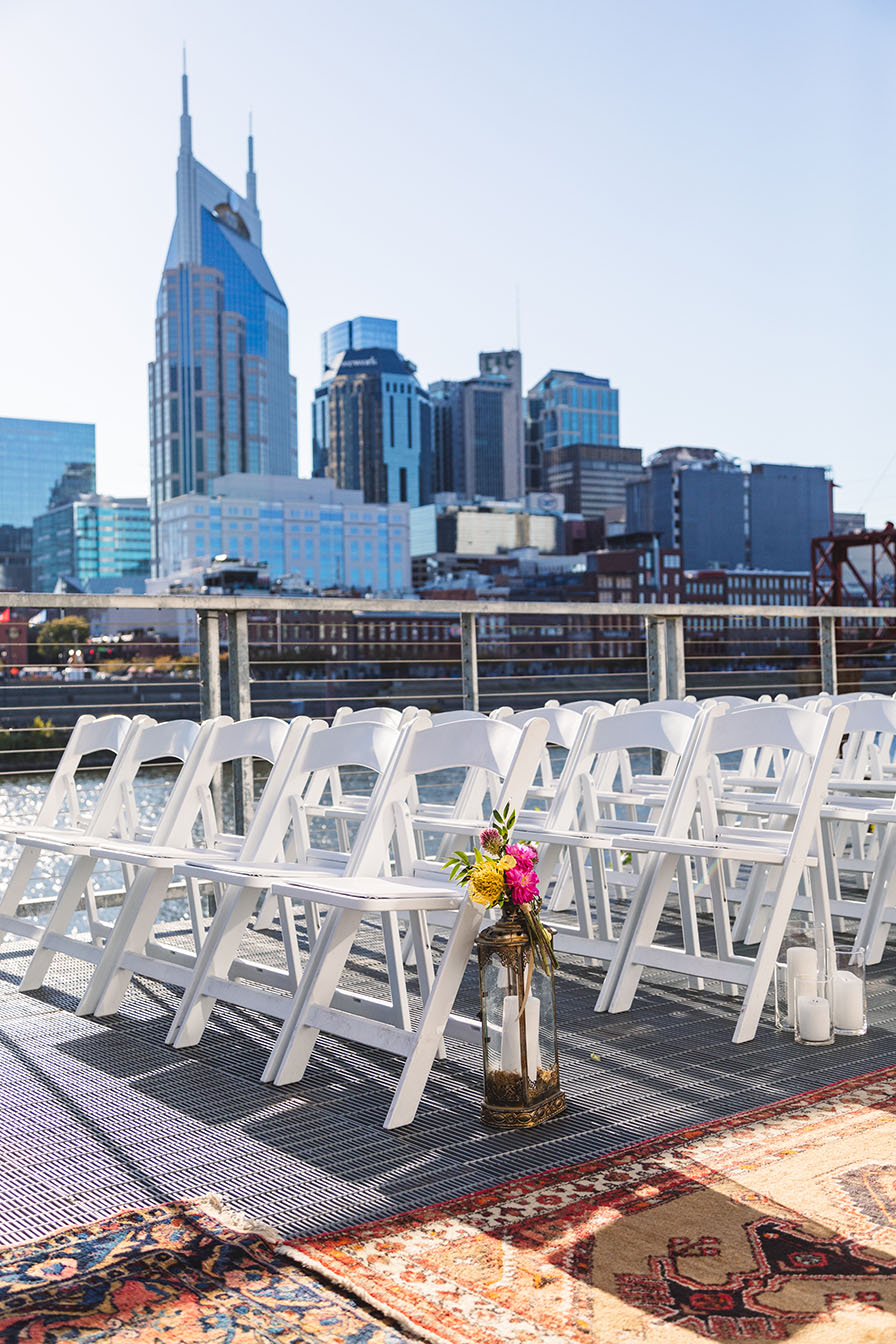 Wedding ceremony setup on the riverfront at the Bridge Building with Nashville skyline in the background and oriental rugs lining the aisle