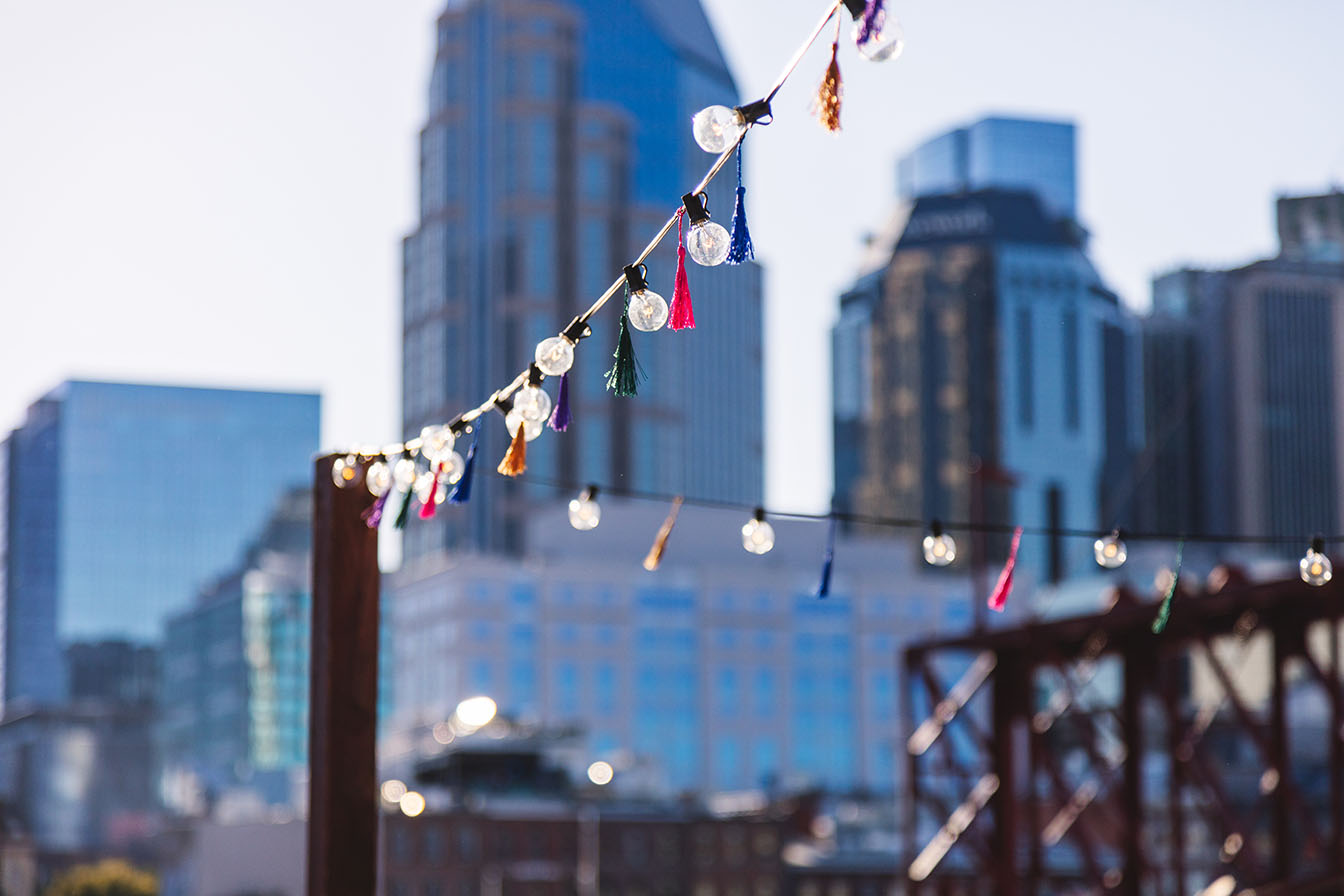 String lights hanging with colorful fringe tassels with Nashville skyline in the background