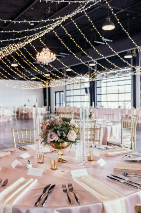 Twinkle light canopy and chandelier hanging over pink wedding reception tables at Cherokee Dock