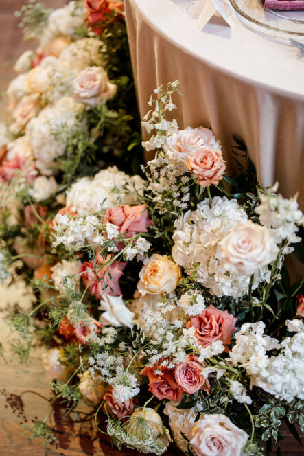 white pink and corral colored florals around the sweetheart table